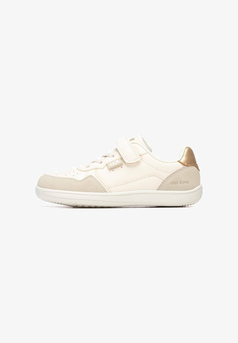 Zapatillas blancas con una combinación de texturas lisas y de ante. Presentan una correa de velcro, un acento dorado en el talón y un diseño perforado en la puntera.