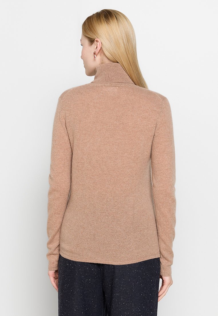 Sweter z golfem w jasnobrązowym kolorze, wykonany z miękkiego materiału. Posiada długie rękawy i luźny krój, gładka struktura bez widocznych wzorów.