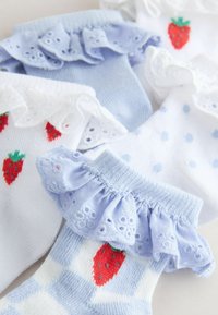 Chaussettes douces pour bébé avec des bordures en dentelle froncée en blanc et bleu clair, ornées de motifs de fraises rouges et de pois bleu clair.