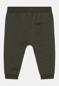 Ciemnozielone spodnie dresowe wykonane z miękkiego materiału, z elastycznym paskiem w talii, zwężanymi mankietami i tylną kieszenią z przeszytym wykończeniem.