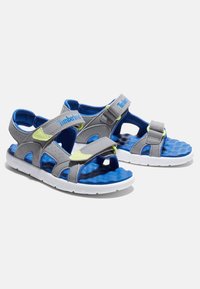Grå och blå sandaler med justerbara remmar, texturerad blå innersula och vit gummisula. Har en lätt design och perforerade detaljer.