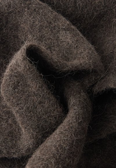 Primer plano de tela de lana suave y rizada de color marrón oscuro con fibras y pliegues visibles que crean sombras texturizadas y profundidad.