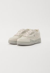 Helle beige Sneakers aus Wildleder und Mesh, mit runden Schnürsenkeln, einer strukturierten Plattformsohle und seitlichen Logo-Details.