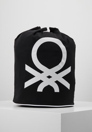 Sac noir de forme cylindrique, arborant un motif graphique blanc distinctif. Fabriqué en matériau durable, il dispose d'une fermeture à cordon en haut.