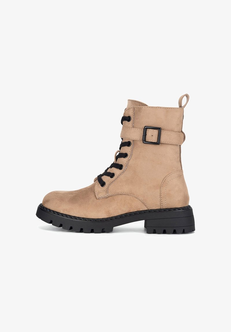 Botines de ante color cuero con suela de goma negra, cordones delanteros y una correa lateral con hebilla cuadrada. Acabado texturizado y lengüeta para tirar.