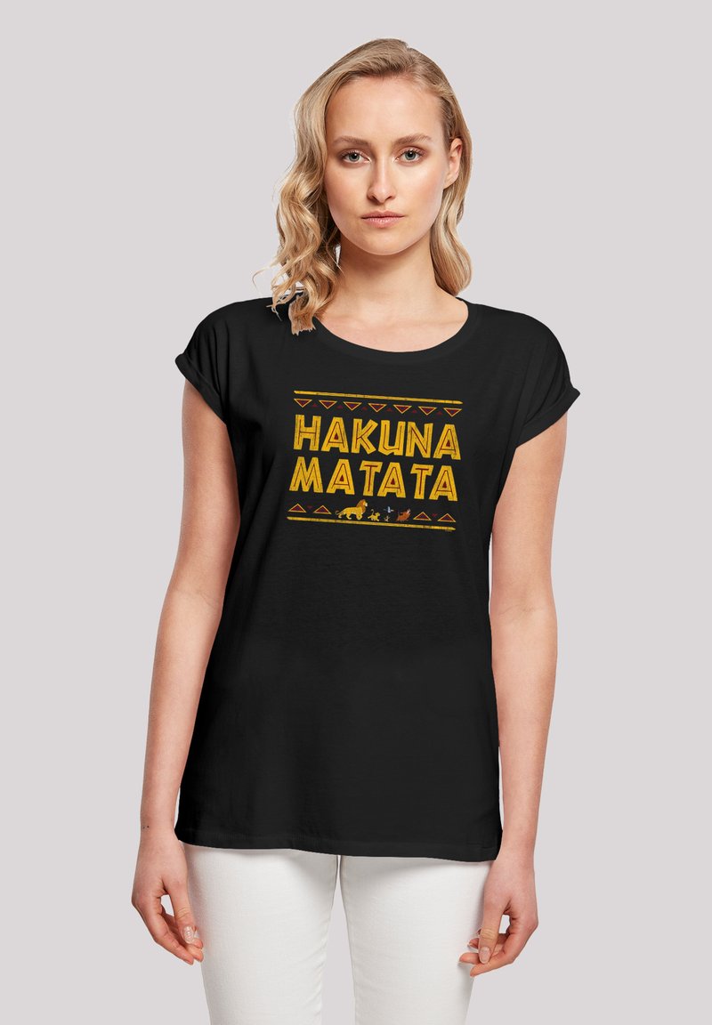 Svart T-skjorte med korte rullede ermer, med en gul "HAKUNA MATATA" tekstdesign og dyreillustrasjoner på fronten.