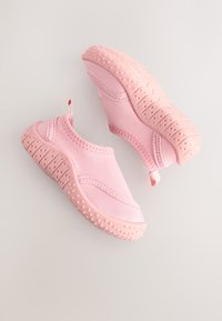 Paire de petites chaussures d'eau roses à enfiler avec semelles texturées pour une meilleure adhérence, conçues pour enfants, présentée sur un fond clair et neutre.