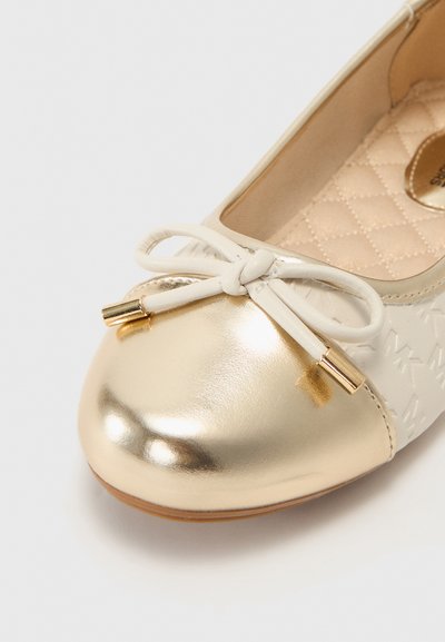 Sapatilha com biqueira metálica dourada e parte superior texturizada em creme. Apresenta um laço com detalhes em metal dourado. Interior acolchoado.