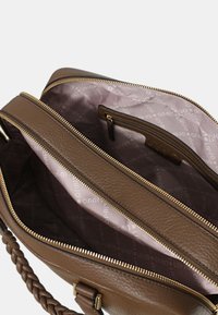 Borsa a tracolla in pelle marrone con manico intrecciato, dotata di chiusura zip e interno foderato con un motivo rosa chiaro e tasca con zip.