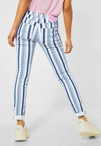 Randiga jeans av denim med ljusblå, marinblå och vita vertikala ränder; slim fit, uppvikt fåll och två bakfickor. Rosa logopatch på midjan.