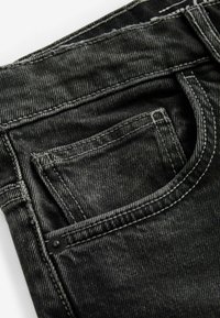Zwarte denim jeans met een voorzak, zichtbare stiksels en een zachte textuur. Kenmerkt zich door een kleine zwarte knop nabij de zak.