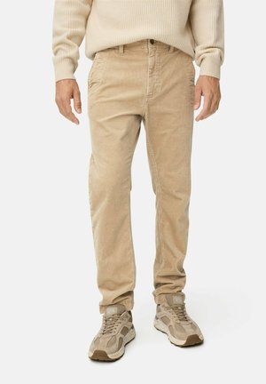 Beige corduroy pants with a relaxed fit, featuring front pockets and subtle vertical ridges. Paired with beige and gray sneakers.