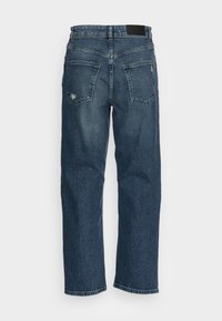 Jeans de mezclilla azul oscuro con un corte recto, con un ligero desgaste, dos bolsillos traseros y una etiqueta negra en la cintura.