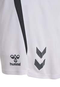 Short de sport blanc avec une bande verticale noire, logo abeille hummel noire et deux flèches chevrons noires vers le bas sur la jambe droite.