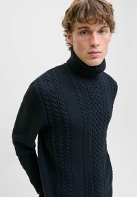 Pull en col roulé bleu marine foncé avec un motif en cable texturé et des accents côtelés. Il dispose de manches longues et d'un design de col haut ajusté.