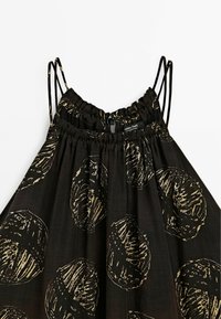 Sort kjole med gyldne cirkelmønstre, med tynde justerbare stropper og en rynket halsudskæring. Blødt, let stof.