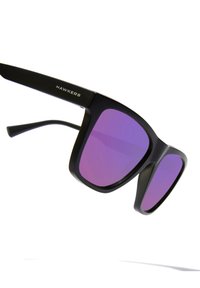Black sunglasses with oversized square frames and gradient purple lenses. Features a sleek matte finish and "HAWKERS" logo on the arm.