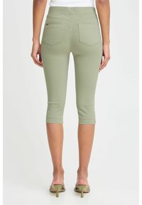 Leggings do kolen, prilegajočega kroja iz svetlo olivno zelene tkanine. Imajo gladek pas in dve zadnji žepi z jasno definiranim šivom.