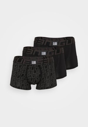 Calzoncillos bóxer negros con un patrón geométrico, pretina elástica y ajuste ceñido, acompañados de pies descalzos y un fondo neutro.