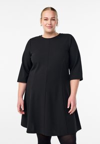 Czarna sukienka z rękawami o długości trzy czwarte, okrągłym dekoltem, w fasonie A-line, gładkim materiale i detalami szwów z przodu i z tyłu.