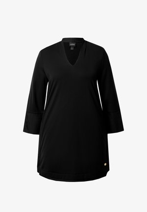 Musta mekko, jossa on V-mallinen kaula-aukko, kolmannes pitkät hartiahihat ja kaareva helma. Alareunassa on pieni kultainen korostustunnus vasemmalla puolella.