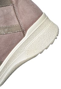 Close-up of beige suede sneaker heel with textured off-white rubber sole and woven fabric detail on white background.