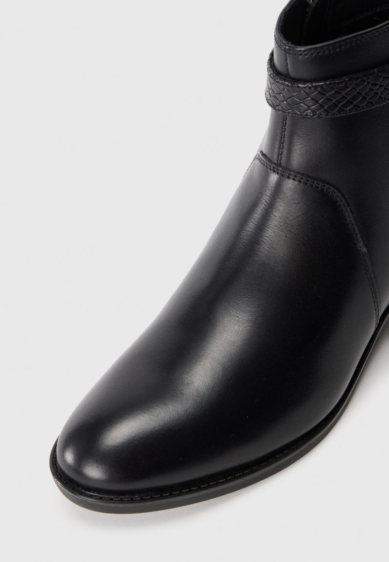 Bottine en cuir noir à bout pointu, avec un col texturé et des détails de couture subtils. Fini de surface lisse et design épuré.