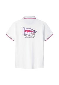 Camisa polo blanca con un diseño en la parte posterior de una bandera a rayas con un motivo de pez y texto, acentuada con colores rojo y marino en los puños.