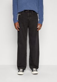 Sorte denim bredde ben jeans med midt livhøyde, med en klassisk fem-lommers design og subtil søm. Kombinert med en blå strikkegenser og sneakers.