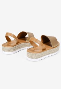 Sandalias de esparto de color tostado con dos correas, una plantilla de cuerda tejida y suela de goma blanca; parte superior de cuero suave y diseño de tacón plano.