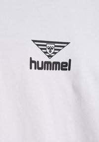 Czarne logo Hummel ze stylizowaną trzmielem w paskowanym, odwróconym trójkącie na białym tle z tkaniny.
