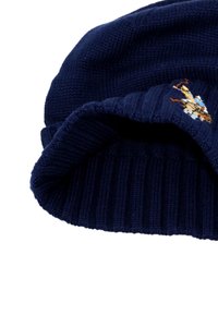 Tengerészkék kötött sapka bordázott mintával, elöl hímzett részlettel. Puha tapintás és hajtott mandzsetta.