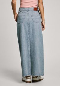 Lichtblauwe denim maxi rok met een rechte snit, voorzien van twee achterzakken en een leren patch op de tailleband.