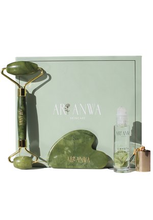 Jade roller, gua sha-steen en flesje Crystal Glow-on weergegeven voor een groene Aranwa Skincare-doos.