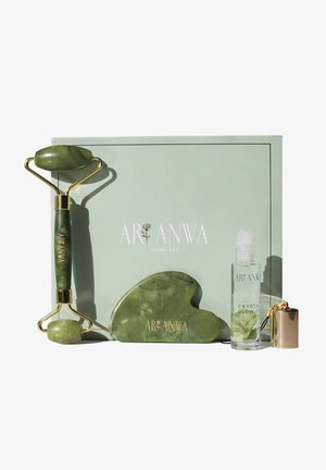Jade roller, gua sha stone, and crystal glow-on bottle displayed in front of a green Aranwa Skincare box.