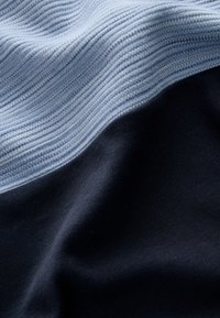 Tessuto strutturato con una divisione orizzontale in azzurro chiaro e blu scuro, che presenta trame a coste e lisce con un aspetto morbido.