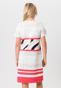 Korte mouw jurk met een combinatie van lichte kleuren en gedurfde horizontale strepen in rood, zwart en wit, gemaakt van een gladde, lichte stof.