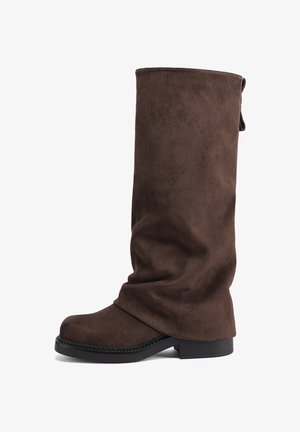 Stivale al ginocchio in suede marrone con design scivoloso, punta rotonda e suola piatta spessa, caratterizzato da cuciture decorative lungo la base.
