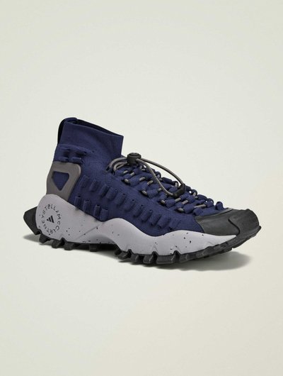 Scarpa sportiva blu navy con tomaia in maglia, dettagli grigi, suola texturizzata e un sistema di allacciatura unico, caratterizzata da un design slip-on.