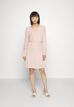 Vestido rosa claro com decote em V, mangas longas e um cós elástico. Tecido texturizado com um padrão subtil, comprimento acima do joelho.
