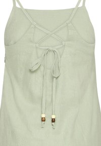 Top senza maniche di un verde chiaro con un design incrociato sul retro. Presenta un nodo frontale con perline di legno e crema. Tessuto morbido e con una texture.