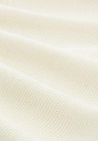 Textiltyg i off-white med en subtil ribbad textur. Mjuk, slät yta med t ätt liggande parallella linjer.