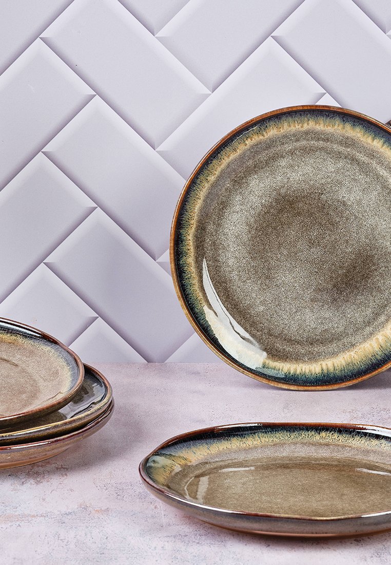 Brązowe ceramiczne talerze o błyszczącej powierzchni, z gradientowym brzegiem w odcieniach niebieskiego i żółtego, ustawione na teksturowanym tle.