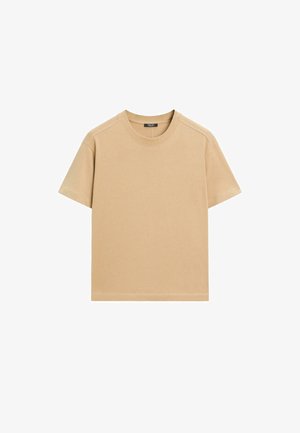 T-shirt en coton beige à manches courtes, col rond et coupe décontractée. Présente une texture lisse et des coutures soignées sans motifs.