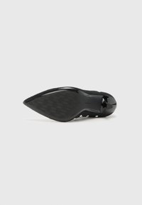 Black high-heeled shoe with a pointed toe and smooth patent finish. The sole features a textured pattern for grip.
