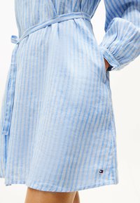 Blåstribet kjole med bælte i taljen, med lange, rynkede ærmer og en lille logo ved kanten. Fremstillet i letvægtsstof.