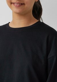 Zwarte katoenen t-shirt met een ronde hals, korte mouwen en een gladde textuur, die het bovenste deel van de borst en de hals toont.
