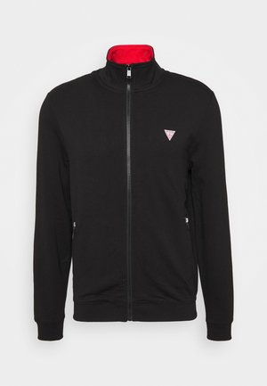 Schwarze Jacke mit Reißverschluss, rotem Innenkragen, zwei vorderen Reißverschlusstaschen und kleinem dreieckigem Logo auf der linken Brust.