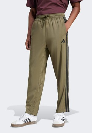 Olijfgroene sportbroek met zwarte strepen, elastische tailleband met trekkoord, tapered fit en ritssluiting bij de boorden.