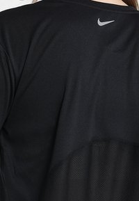 Schwarzes Sportshirt aus glattem, leichtem Stoff mit atmungsaktivem Mesh-Einsatz im unteren Rückenbereich. Nike-Logo in Grau am Halsausschnitt.